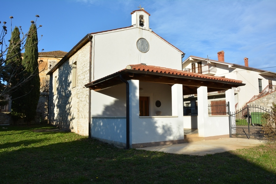 L'immagine mostra la chiesa di San Giuseppe nell'abitato di Fiorini. Di fronte e di lato si vede un prato ben curato, e ai margini del terreno dietro la chiesa si vedono i cipressi. La chiesa è stata ristrutturata.