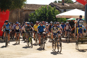 Na slici se u prvom planu vidi biciklistička utrka. Biciklisti svi zajedno prolaze kroz centar naselja. U pozadini se mogu vidjeti stare kuće naselja, sa desne i lijeve strane šareni suncobrani daju naslutiti da je u tijeku lokalna fešta.
